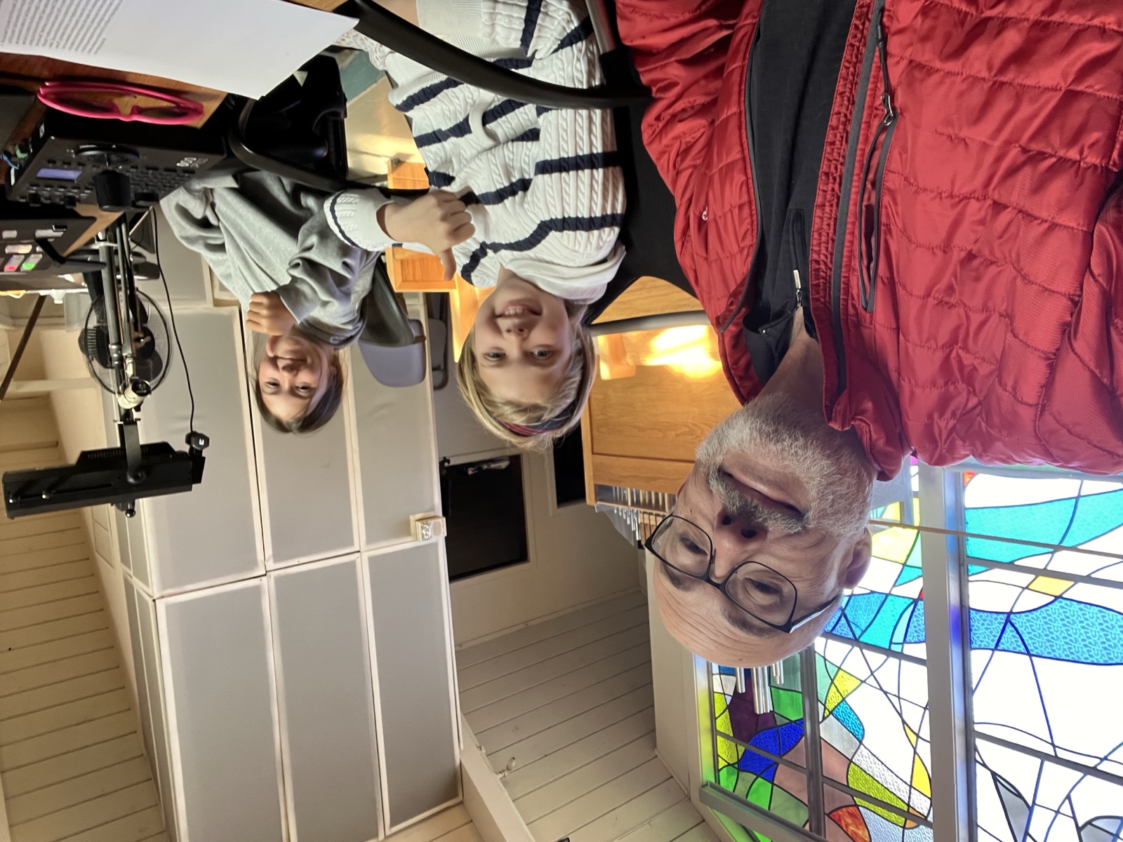 Jim with two new volunteers giving thumbs up after a Mass
